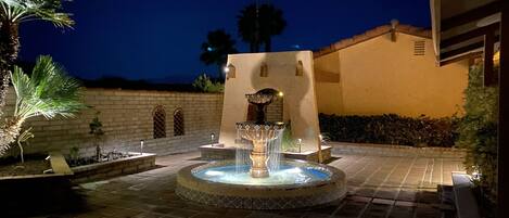 A fountain with water jets in a courtyard at night.