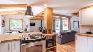 A modern kitchen with wooden beams, a large stove, and a dining area with a sofa. - Chalet Scandinavian,  Turn Key Amenities + Pet Friendly + Dedicated Workspace with Hi Speed WiF (Orford)