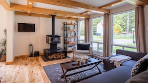 A modern living room with a fireplace, sofa, and large windows. - Chalet Scandinavian,  Turn Key Amenities + Pet Friendly + Dedicated Workspace with Hi Speed WiF (Orford)