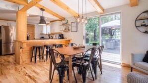 A modern kitchen with wooden beams, a central island, bar stools, and a dining table. - Chalet Scandinavian,  Turn Key Amenities + Pet Friendly + Dedicated Workspace with Hi Speed WiF (Orford)