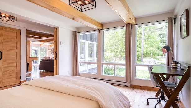 A bedroom with a large bed, a desk with a chair, and large windows offering a view of the outdoors. - Chalet Scandinavian,  Turn Key Amenities + Pet Friendly + Dedicated Workspace with Hi Speed WiF (Orford)