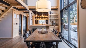 A spacious dining area with a wooden table and chairs, a hanging light fixture, and a view of the outdoors through large windows. - Chalet Denmark, Turn Key Amenities + Pet Friendly + Dedicated Workspace with Hi Speed WiF (Orford)
