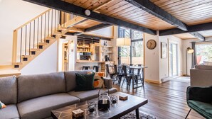 A modern living room with a wooden staircase, a sofa, a coffee table, and a dining area. - Chalet Denmark, Turn Key Amenities + Pet Friendly + Dedicated Workspace with Hi Speed WiF (Orford)