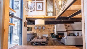A spacious loft-style living area with a large wooden dining table, a fireplace, and a cozy seating area. - Chalet Denmark, Turn Key Amenities + Pet Friendly + Dedicated Workspace with Hi Speed WiF (Orford)