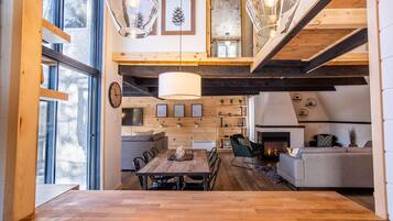 Un vaste espace de vie aménagé dans un style loft, avec une grande table à manger en bois, une cheminée et un coin salon confortable.
