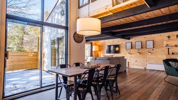 A spacious room with a large dining table, black chairs, a sofa, and a TV mounted on the wall. - Chalet Denmark, Turn Key Amenities + Pet Friendly + Dedicated Workspace with Hi Speed WiF (Orford)