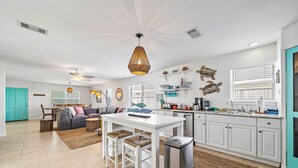 A modern kitchen with white cabinets, a white island, and a teal door. - Galveston Gem: Two Homes, Pool & More Amenities (Galveston)