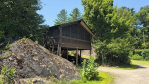 A cabin with a wooden deck, surrounded by dense trees and a dirt path. - ADK Rustic Private Chalet Viewing Two Ponds / Forest 5.3 miles To Gore Mountain (North Creek)