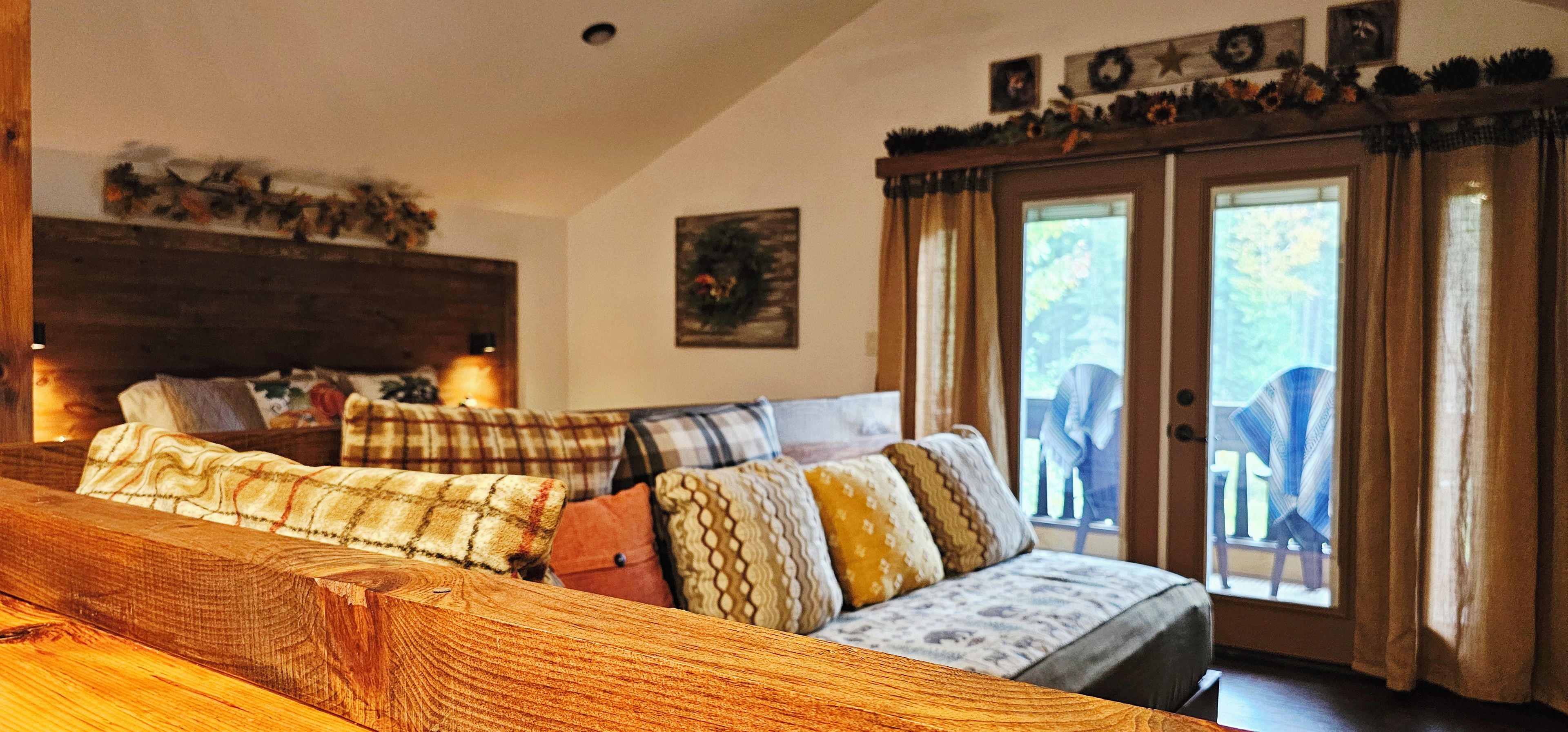 A cozy living room with a sofa set, a wooden coffee table, and a large window with curtains.