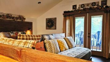 A cozy living room with a sofa set, a wooden coffee table, and a large window with curtains.