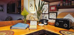 A wooden reception desk with a book, a vase with yellow flowers, a telephone, a basket, and framed welcome signs.