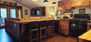 A kitchen with a bar area, wooden cabinets, a stove, and a microwave. - ADK Rustic Private Chalet Viewing Two Ponds / Forest 5.3 miles To Gore Mountain (North Creek)