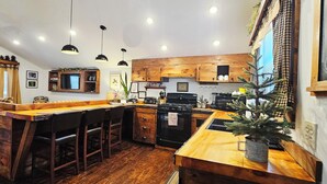 A kitchen with wooden cabinets, a bar area, and pendant lighting. - ADK Rustic Private Chalet Viewing Two Ponds / Forest 5.3 miles To Gore Mountain (North Creek)