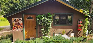 Une cabane en bois avec une porte, des fenêtres et une pancarte indiquant « Bienvenue ».