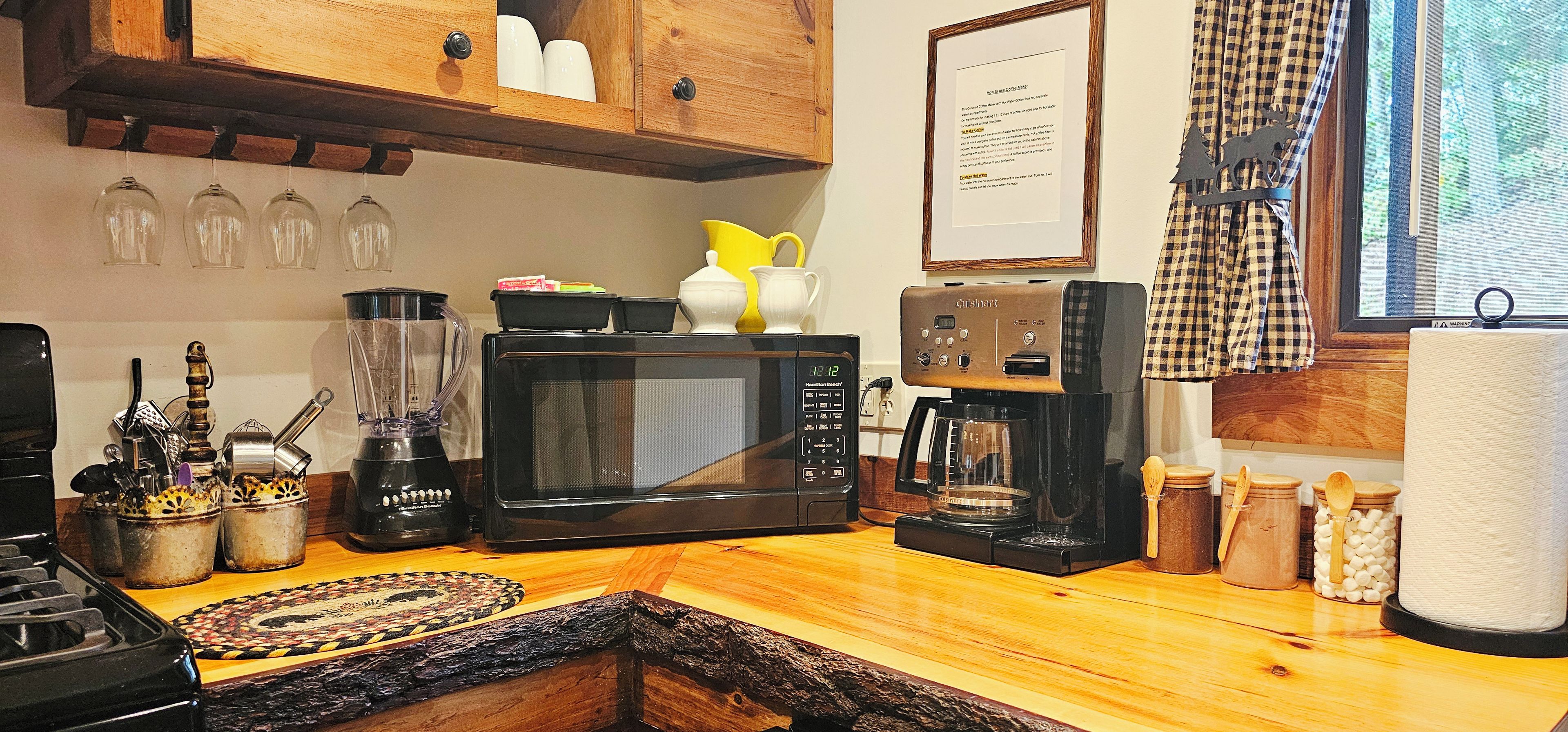 A kitchen with a microwave, coffee maker, and various utensils.