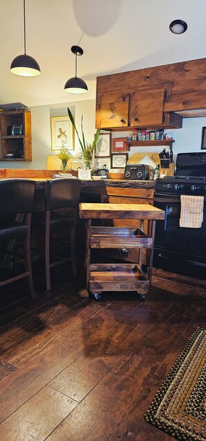 Een keuken met houten kastjes, een zwarte kookplaat en een bar met krukken.