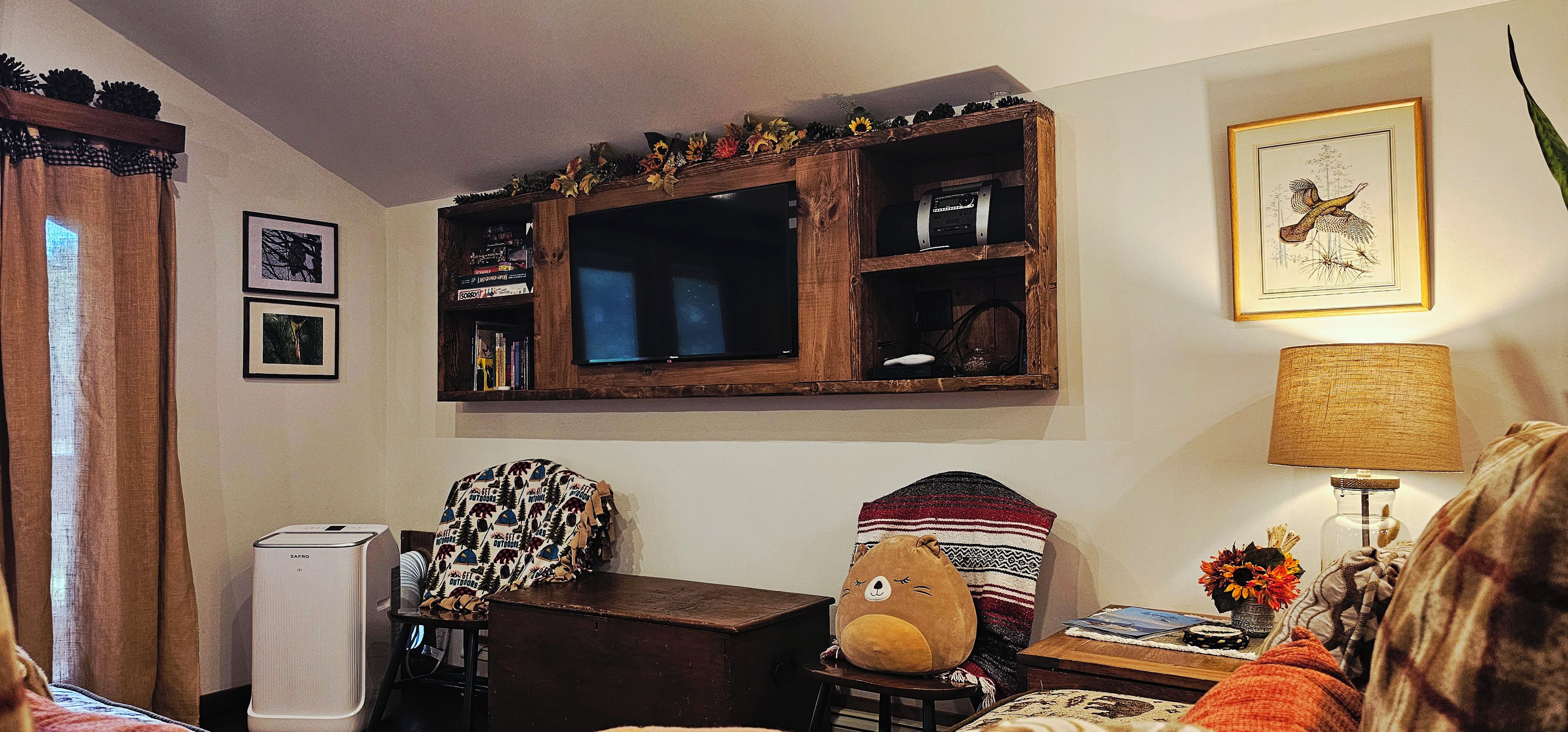 A cozy living room with a wooden entertainment unit, a sofa, a lamp, and a decorative bear on a side table.