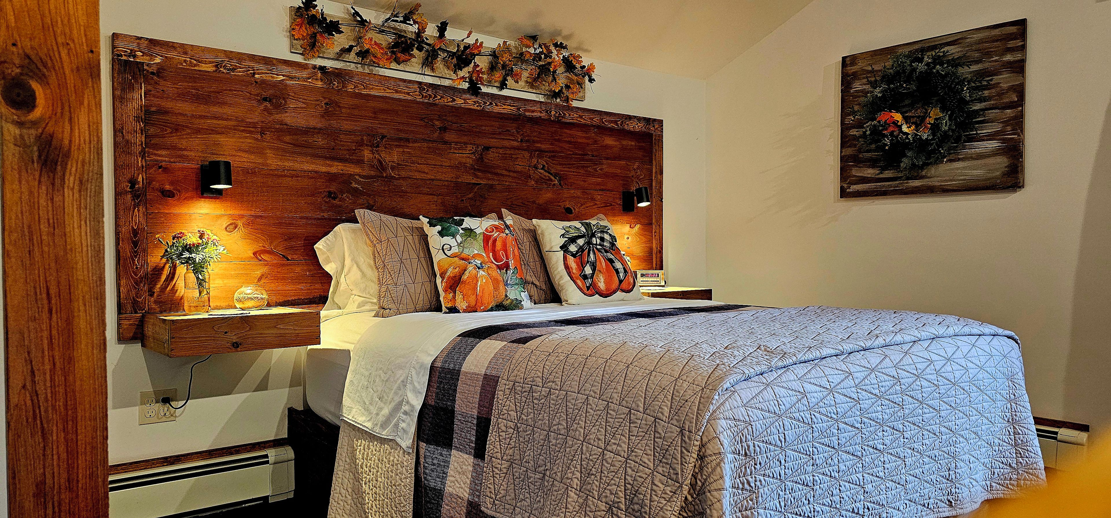 A bedroom with a wooden headboard, a bed with a patterned quilt, and decorative pillows.