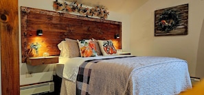 Une chambre à coucher avec une tête de lit en bois, un lit recouvert d’une courtepointe à motifs et agrémenté de coussins décoratifs.