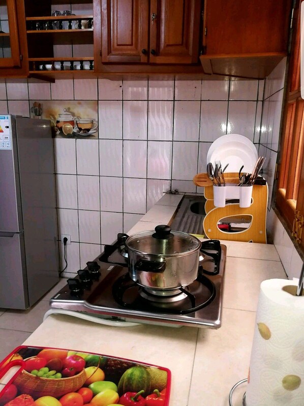 Efficient kitchen with gas stove, refrigerator, and ample storage.