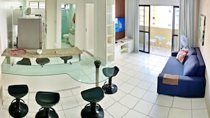 A modern living room with a glass dining table, black chairs, a blue sofa, and a TV. - Vacanze - Monteverdi (Maceió)
