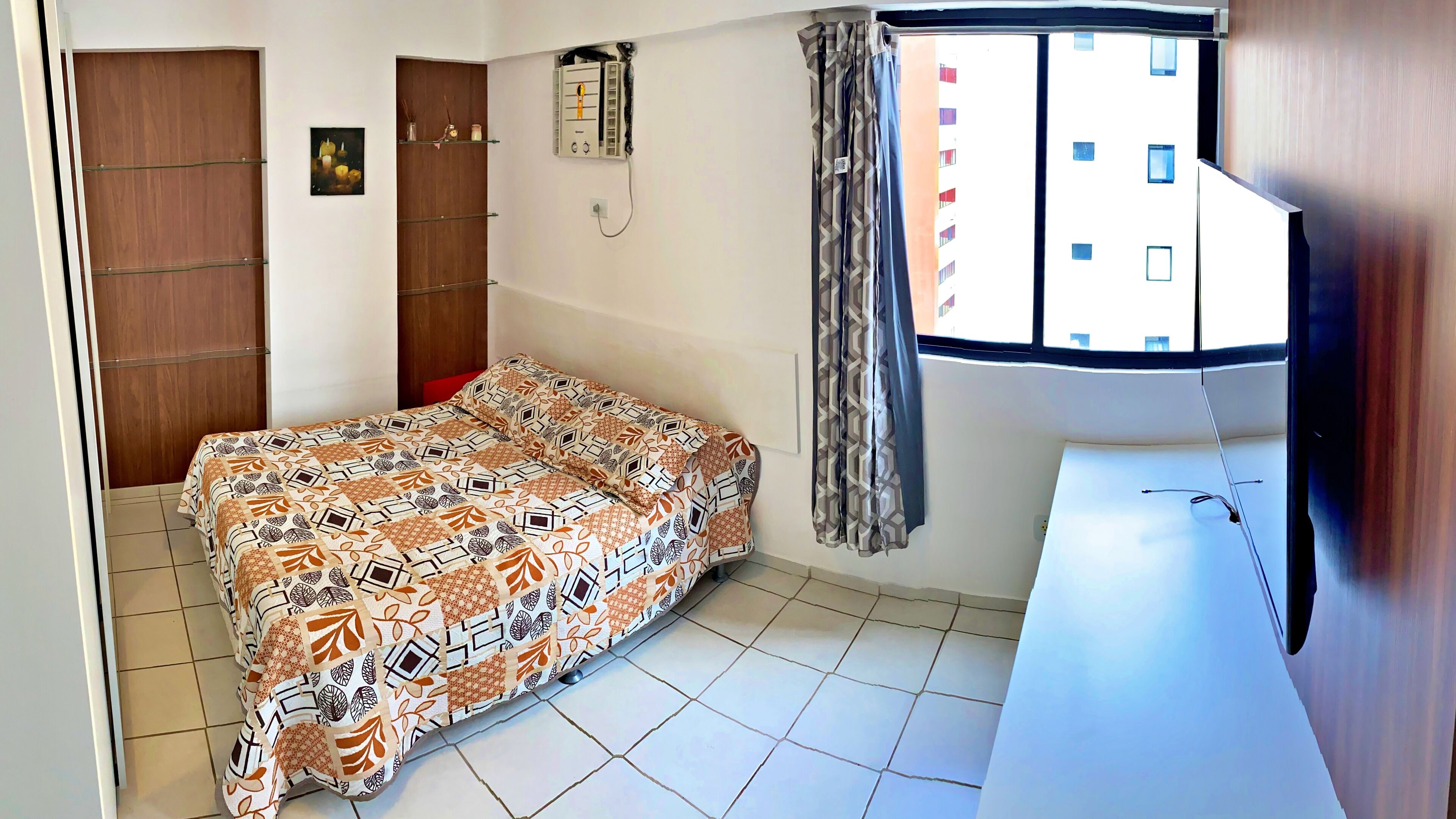 A bedroom with a bed, a desk, a window, and a door.
