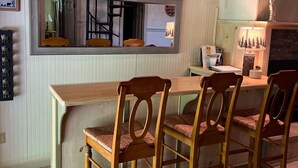 A dining area with a wooden table and chairs, a large mirror, and a window with a view of trees. - Cozy Chalet with First Lake access just minutes from town.  Great Location (Old Forge)