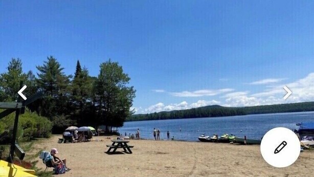 A lakeside beach with picnic tables, umbrellas, and boats. - Cozy Chalet with First Lake access just minutes from town.  Great Location (Old Forge)