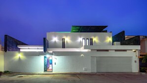 Un edificio moderno de dos pisos con puerta de garaje, entrada bien iluminada y un número de domicilio visible.