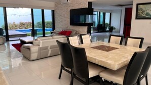 Una sala de estar moderna con una gran mesa de comedor, un sofá y un televisor montado en la pared.