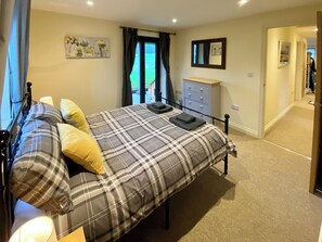 A bedroom with a bed, a dresser, a mirror, and a window with curtains. - 3 bedroom accommodation in Foxley, near Dereham (Foxley, near Dereham)