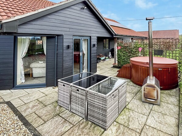 A modern house with a patio, a hot tub, and a wood-fired oven.