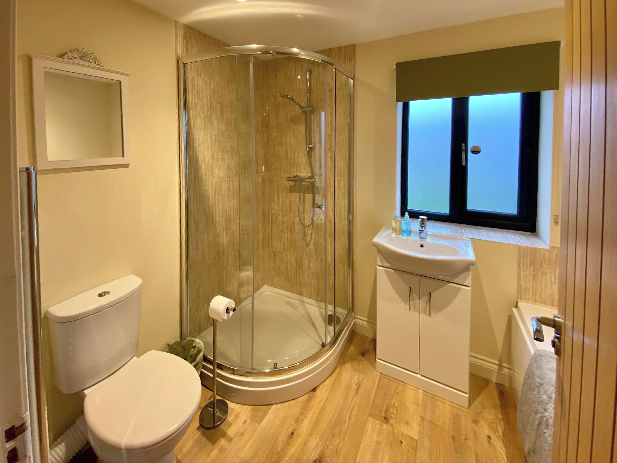 Une salle de bain avec une douche à parois de verre, des toilettes, un lavabo et une fenêtre.
