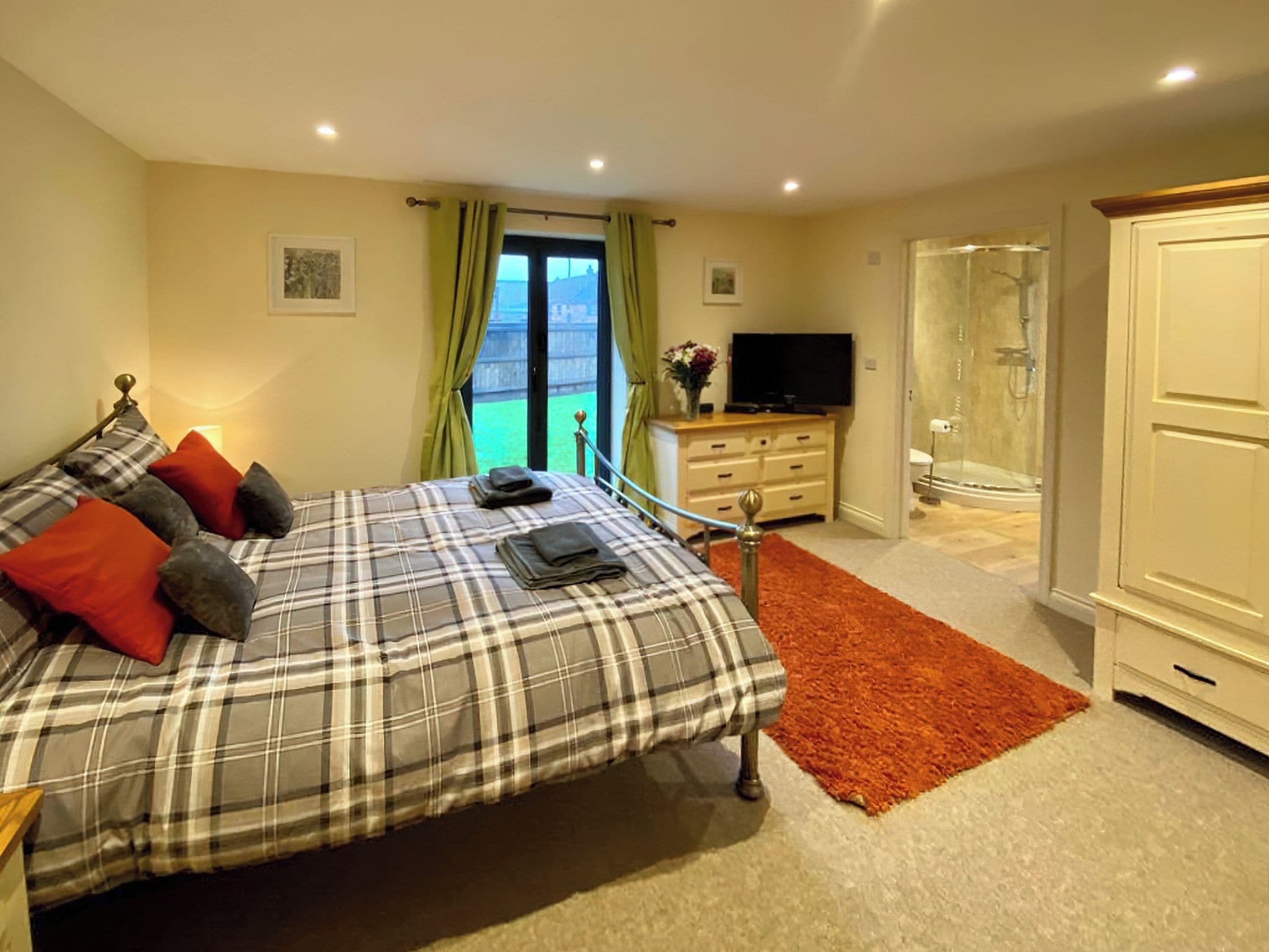 Ein Schlafzimmer mit einem Bett, einem Fernseher, einer Kommode und einer Dusche.