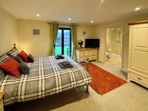 A bedroom with a bed, a TV, a dresser, and a shower.
