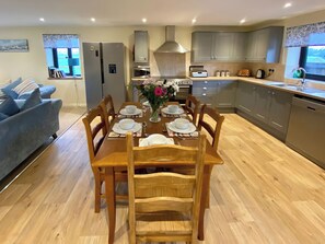 A modern kitchen with grey cabinets, a dining table set for four, and a view of the outdoors through the windows.