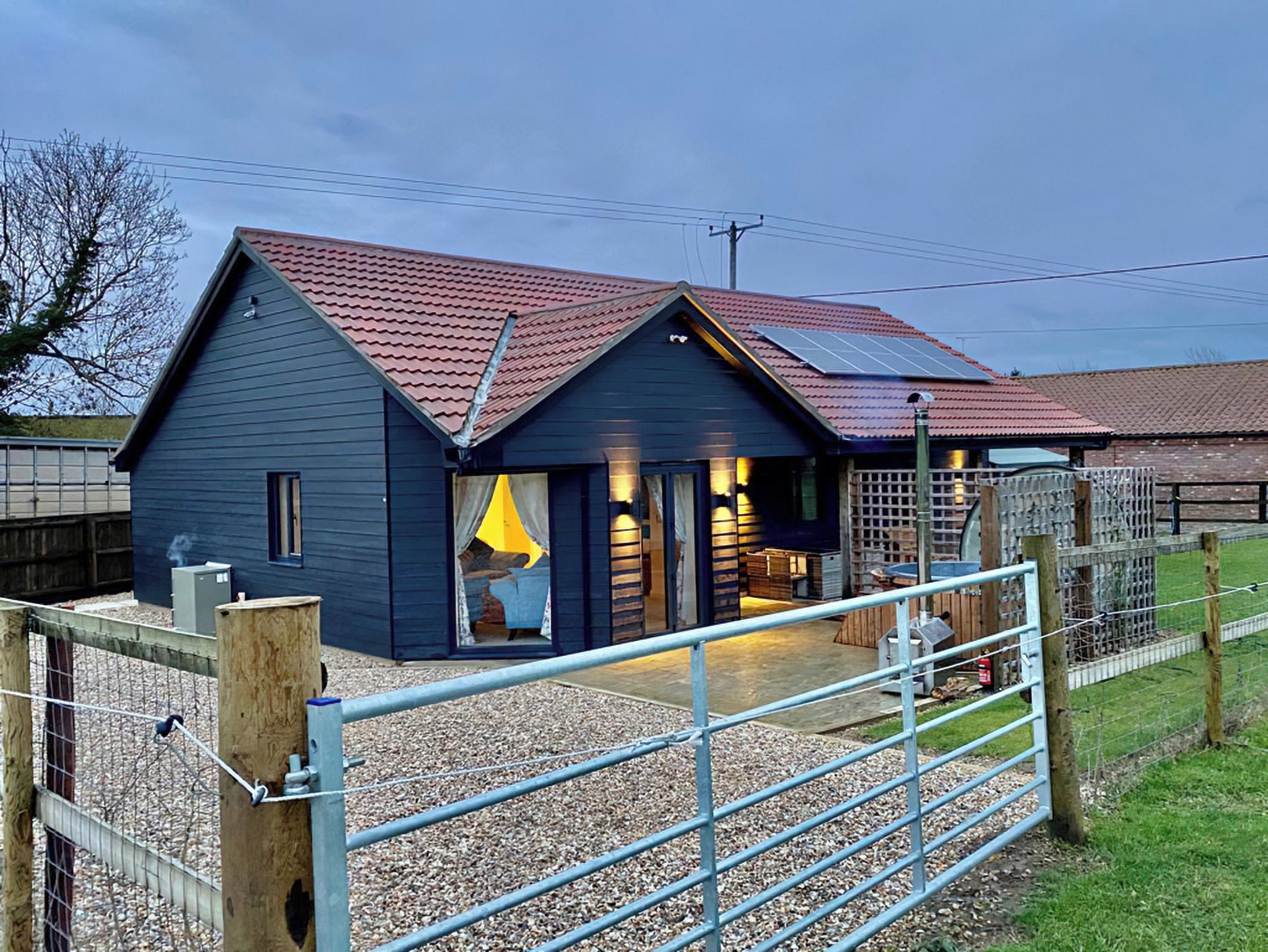 A blue building with a red roof, a gated entrance, and a gravel driveway.