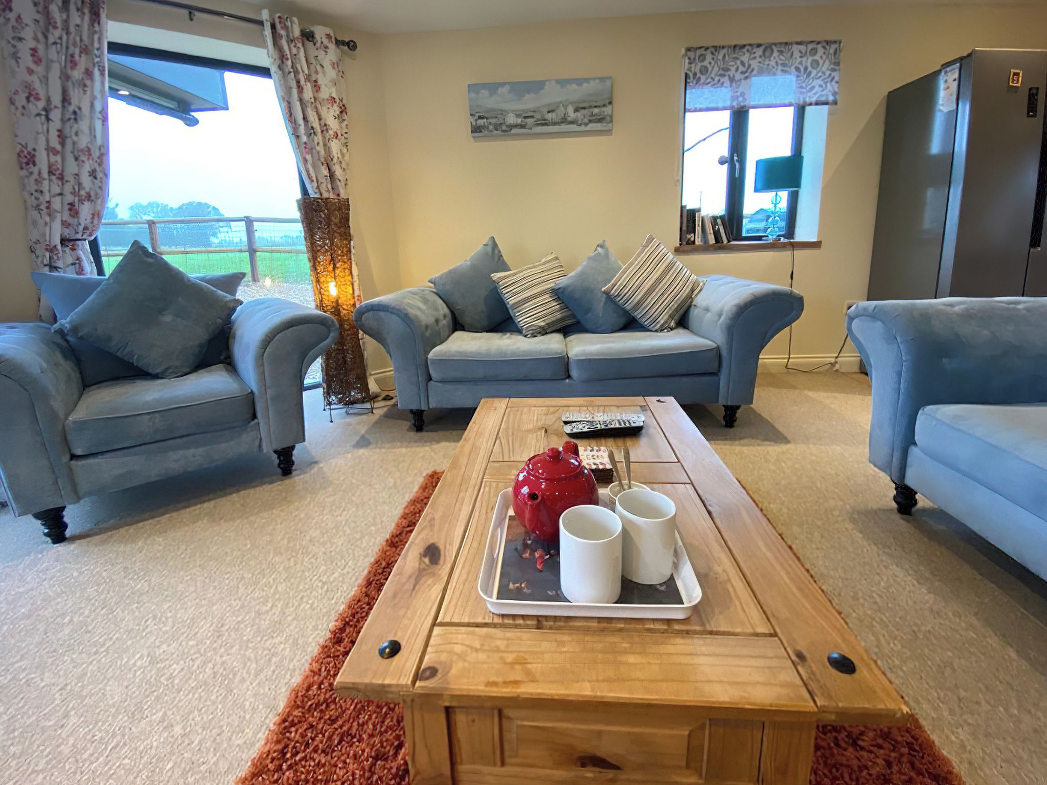 A living room with two sofas, a coffee table with a tray of items, and a view of the outdoors.