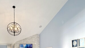 A bedroom with a large bed, a fireplace, a chandelier, and artwork on the walls.