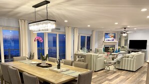A spacious living room with a large TV, a fireplace, and a dining area with a wooden table and chairs.