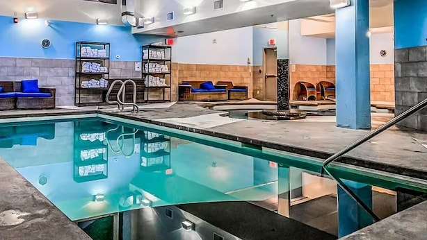 A modern indoor pool area with blue seating and towel racks. - Upgraded Cozy 3 Bdrm Corner Suite, Great Mountain Views, Resort and Spa (Canmore)