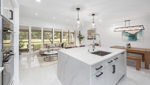 Una cocina moderna con una isla grande, armarios blancos e iluminación colgante.