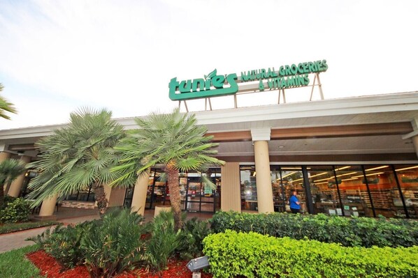 A TUNES natural groceries & vitamins store with palm trees and shrubs in front.