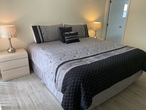 A neatly made bed with a patterned bedspread and pillows, two bedside lamps, and a wooden floor.