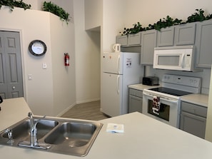 A modern kitchen with grey cabinets, a stainless steel sink, a microwave, a toaster, and a stove.