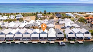 Un quartier résidentiel situé sur la côte, composé de plusieurs maisons, d’un port de plaisance avec des bateaux et offrant une vue dégagée sur l’océan.