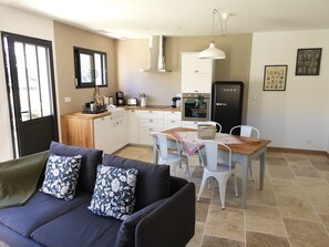 A compact living space with a sofa, dining table, and kitchenette. - LOU MIYA - Gîte Périgourdin 5kms from SARLAT, Air conditioning, Jacuzzi SPA WELLIS (Carsac-Aillac)