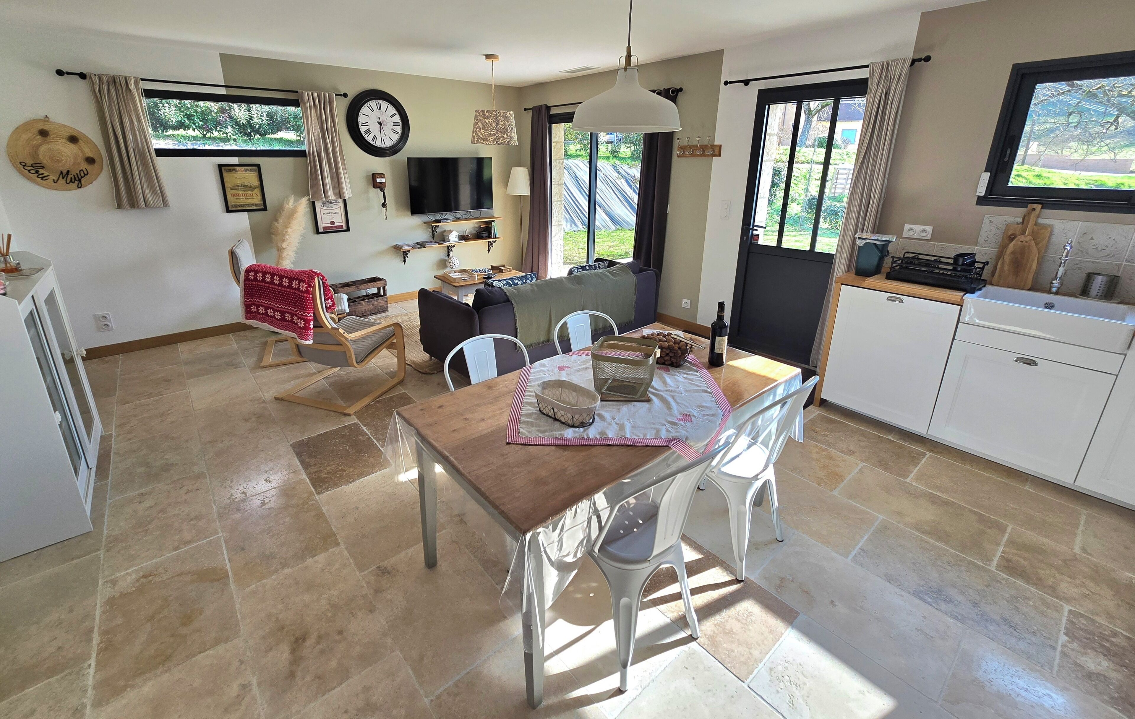 A spacious living area with a dining table, chairs, a sofa, and a TV.