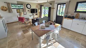 A spacious living area with a dining table, chairs, a sofa, and a TV.