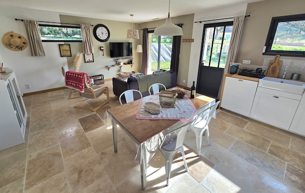 A spacious living area with a dining table, chairs, a sofa, and a TV. - LOU MIYA - Gîte Périgourdin 5kms from SARLAT, Air conditioning, Jacuzzi SPA WELLIS (Carsac-Aillac)